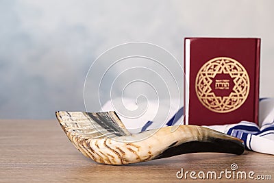 Shofar, Tallit and Torah book with text in Hebrew on wooden table indoors. Rosh Hashanah holiday attributes Stock Photo