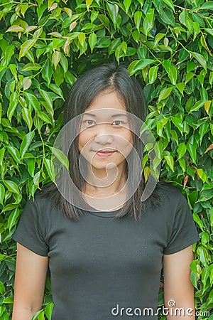 Shoot photo Asian woman portrait wear black t-shirt and smiling with green tree background. Stock Photo