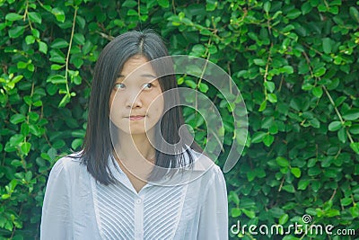 Shoot photo Asian woman portrait wear white shirt, thinking and looking sideways with green tree background. Stock Photo