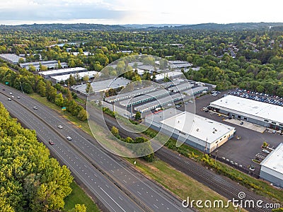 Shooting from a drone. Large highway, industrial buildings. Lots of greenery. In the background is a small green suburb with Editorial Stock Photo