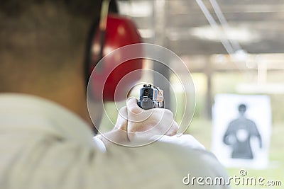 Shooting with Gun at Target in Shooting Range. Man Practicing Fire Pistol Shooting. Stock Photo