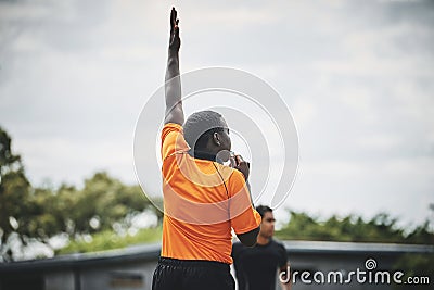 He shoots and scores. a referee blowing his whistle while lifting his hand up in the middle of a rugby match on a field Stock Photo