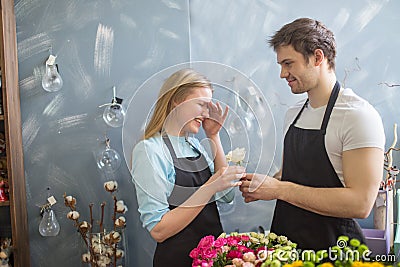 Shop assistant giving flower to his embarrased collegue Stock Photo
