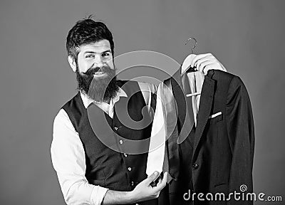 Shop assistant or personal stylist service. Matching necktie outfit. Man bearded hipster hold neckties and formal suit Stock Photo