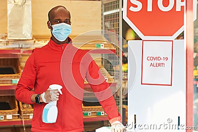 Shop employee at the entrance of the supermarket spraying disinfectant on customers hands Stock Photo