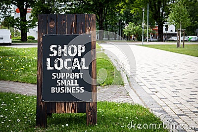 Shop Local. Support small business. Wooden billboard on the street, sunny day Stock Photo