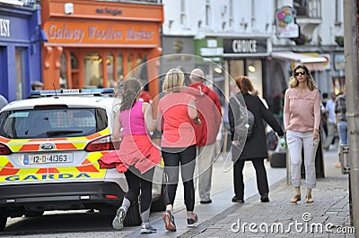 Shop Street, Galway, Ireland june 2017 , Man and dougther joggin near to a Garda car. Editorial Stock Photo