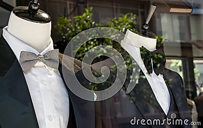 Shop window of mens tailor shop showing 2 mannequins in tuxedos. Stock Photo