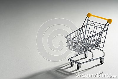 Shopaholic. Buyer. Shopping concept. Close-up. An isolated trolley and shopping basket on a ivory background bisected Stock Photo