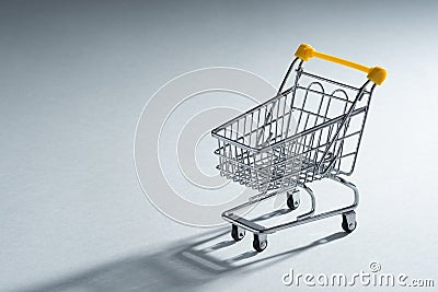 Shopaholic. Buyer. Shopping concept. Close-up. An isolated trolley and shopping basket on a ivory background bisected Stock Photo