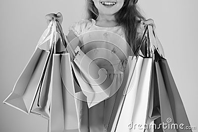 Shopaholic and childhood concept. Lady shopper in dress, wavy hair. Girl holds shopping bags Stock Photo