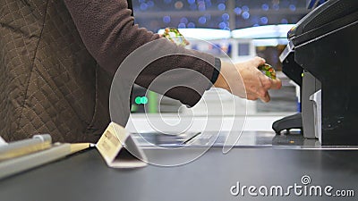 Shopper paying for products at checkout. Foods on conveyor belt at the supermarket. Cash desk with cashier and terminal Stock Photo