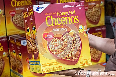 Shoppers hand holding a family size package of Honey Nuts cheerios brand cereals Editorial Stock Photo