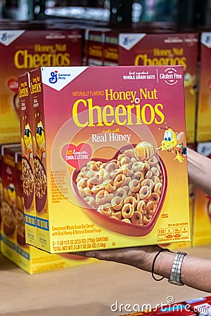 Shoppers hand holding a family size package of Honey Nuts cheerios brand cereals Editorial Stock Photo