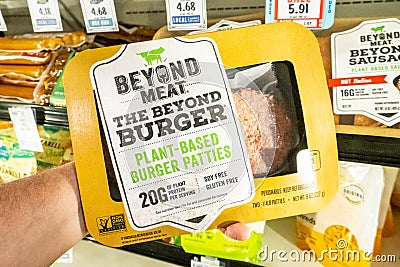 Shoppers hand holding a package of Beyong Meat brand plant based burger patties Editorial Stock Photo