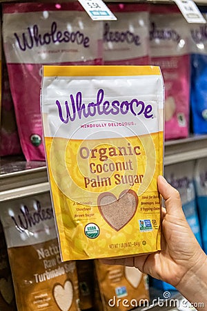 Shoppers hand holding a package of Wholesome brand Organic Coconut Palm Unrefined Brown Sugar Editorial Stock Photo