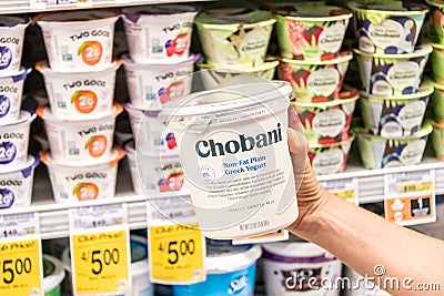 Shoppers hand holding a plastic container of Chovani brand 0% milkfat free Greek yogurt Editorial Stock Photo