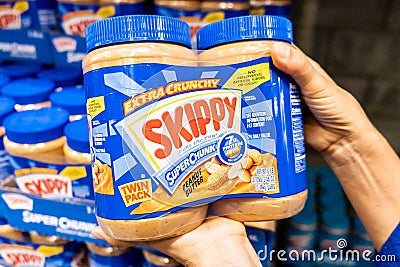 Shoppers hand holding a Twin Pack Plastic Jars of Skippy brand peanut butter Editorial Stock Photo