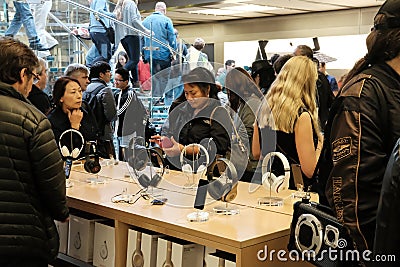 Shoppers and members of the public seen in a well-known retail store, trying headphones and other related accessories. Editorial Stock Photo