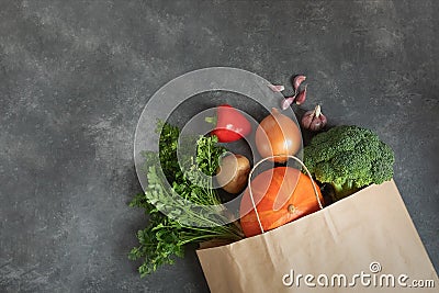 Shopping bag paper full of fresh organic vegetables on dark background. Stock Photo