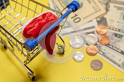 Shopping basket, santa hat, dollars and cents on a yellow background. Selective focus. The concept of Christmas discounts, New Stock Photo