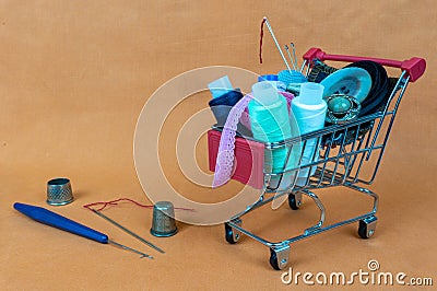 A shopping basket with threads and buttons. Next to thimbles and tools for sewing and embroidery. The background is made Stock Photo