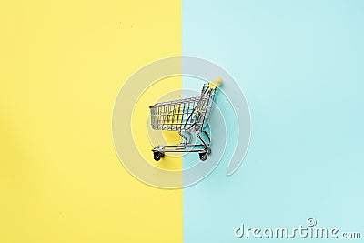 Shopping cart on blue and yellow background. Minimalism style. Creative design. Top view with copy space. Shop trolley Stock Photo