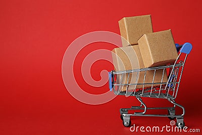 Shopping cart with boxes on red background. Logistics and wholesale concept Stock Photo