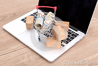 A shopping cart and express parcel full of Canadian dollar bills on a laptop keyboard Stock Photo