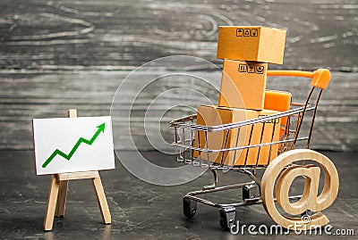 Shopping cart filled with boxes, email symbol and stand with green up arrow. shopping online. Growth rate of Internet sales Stock Photo