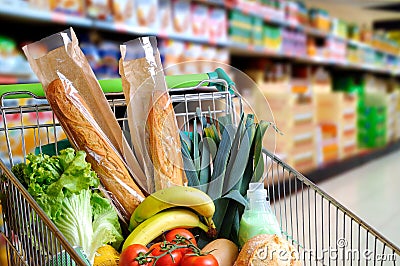 Shopping cart full of food in supermarket aisle elevated view Stock Photo