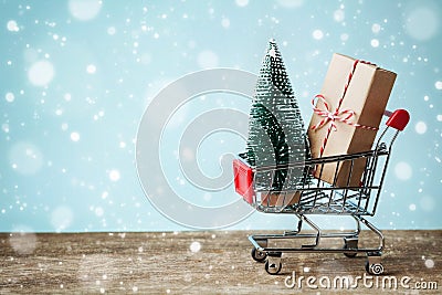 Shopping cart with gift or present and fir tree on snowy effect background. Christmas and New year sale concept. Greeting card. Stock Photo