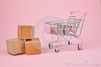 Shopping cart with package boxes on pink background. Shopping and delivering concept. Shop trolley full of parcels Stock Photo