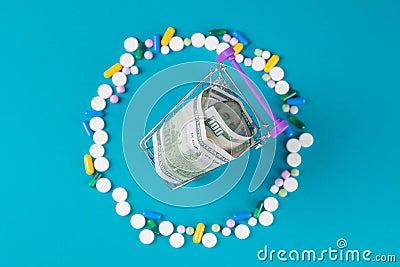Shopping cart with tablet blisters and dollar banknote. Spending money on pills and expensiveness of medicine concept Stock Photo
