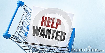 Shopping cart and text HELP WANTED on white paper note list. Shopping list concept on blue background Stock Photo