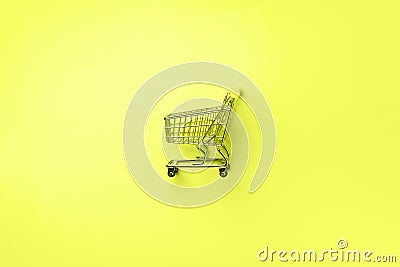 Shopping cart on trendy neon yellow color background. Minimalism style. Creative design. Shop trolley at supermarket. Sale, Stock Photo