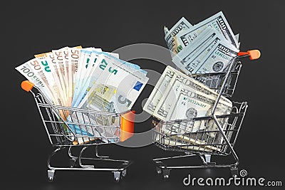 Shopping carts with rival currencies US dollar bills and Euro. Stock Photo