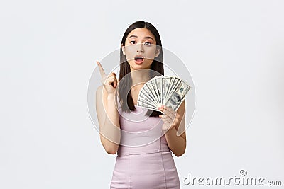 Shopping, holidays and people emotions concept. Attractive korean woman in evening dress, showing money and raise index Stock Photo