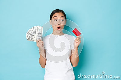 Shopping, money and finance concept. Amazed beautiful asian girl in white t-shirt gasping astonished and looking at Stock Photo