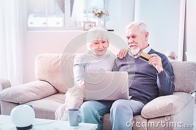 Bearded elderly man holding bank card shopping online with wife Stock Photo