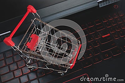 Shopping online concept - shopping cart on the black keyboard. Red mettal trolley on a laptop keyboard. Shopping service on the Stock Photo