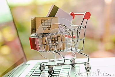 Shopping online concept - Parcel or Paper cartons with a shopping cart logo and credit card in a trolley on a laptop keyboard. Stock Photo