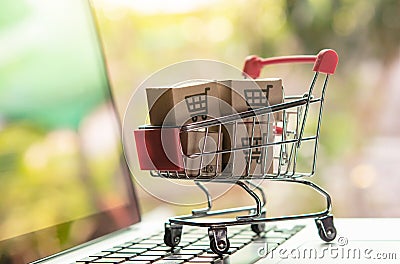 Shopping online concept - Parcel or Paper cartons with a shopping cart logo in a trolley on a laptop keyboard. Shopping service on Stock Photo