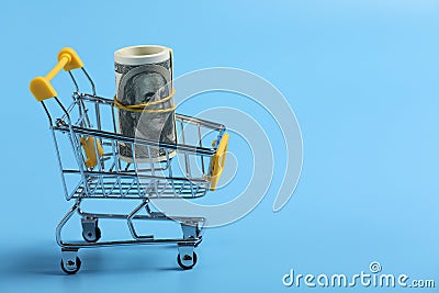 Shopping time. dollars roll in shopping cart on blue background. time is money. Time management concept. money in the basket. Stock Photo