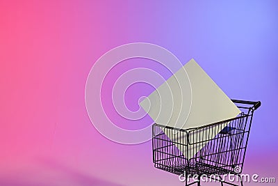 Shopping trolley with blank canvas and copy space over neon purple background Stock Photo