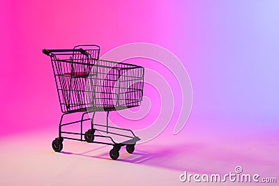 Shopping trolley with copy space over neon purple background Stock Photo