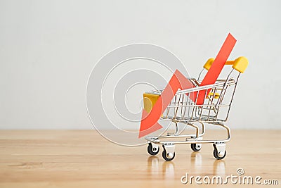 Shopping trolley with red chart falling down on wooden table background copy space. Economic recession crisis, core retail sales Stock Photo