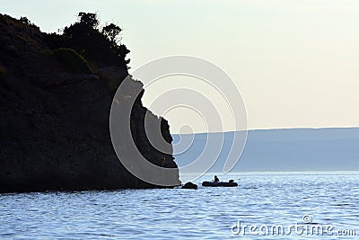 A shore, a boat and a man at hte evening Stock Photo