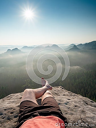 Short break on the mountain trek. Man sit or lay down on the cliff edge Stock Photo