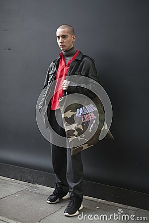 a short-cropped serious young man dressed in a sporting style posing during the London Fashion Week. Editorial Stock Photo